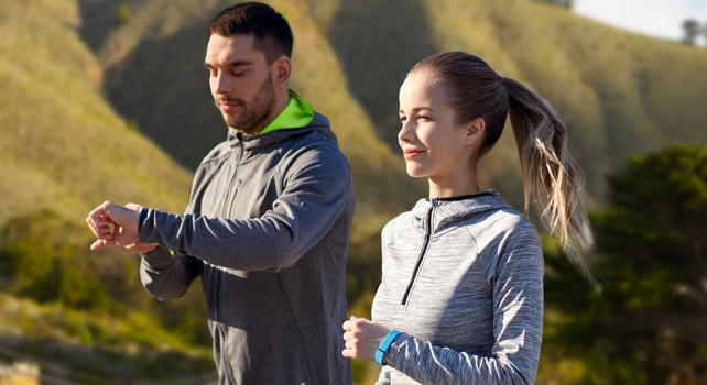 two people walking looking at a fitness tracker
