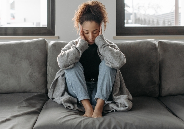 woman sitting on a couch with her head in her hands