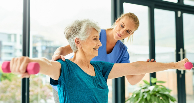 Elderly Woman Lifting Weights With Physio Guidance