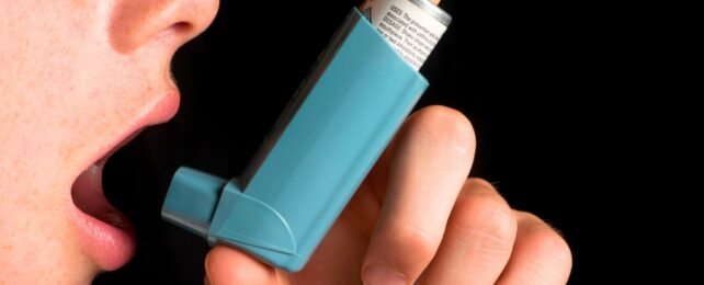Hand holding inhaler to mouth