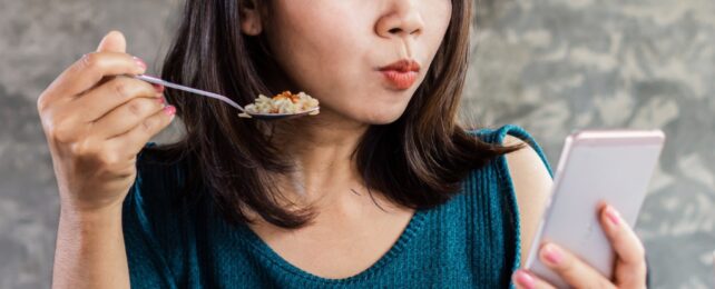 woman on phone while eating