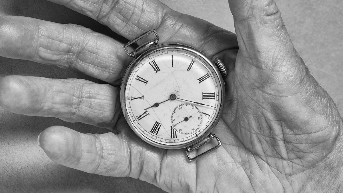 A cracked antique wristwatch face in an old woman's hand