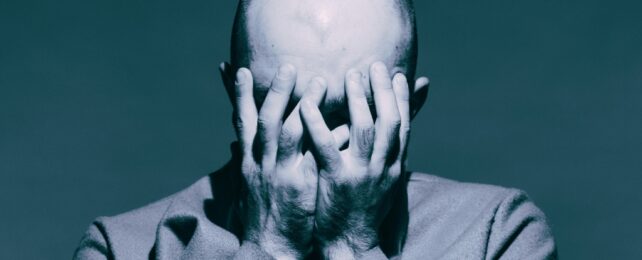 bald man covering his face