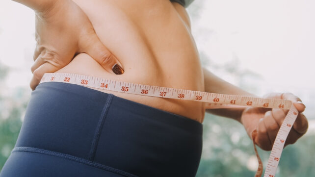 woman measuring her waistline