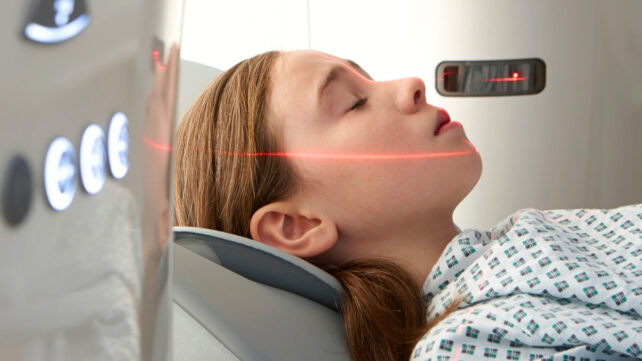 Girl with eyes closed going into CT scanner