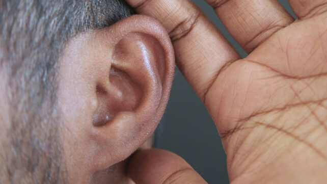 Close up side profile of a man's hand behind his ear
