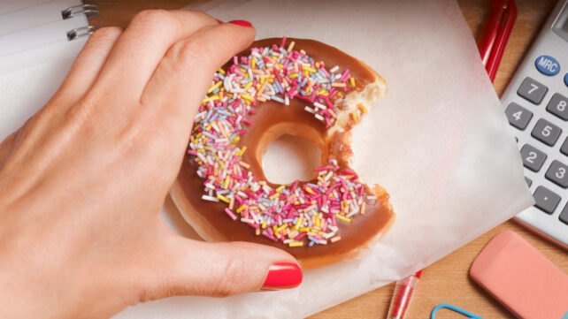 hand holding a donut with chocolate icing