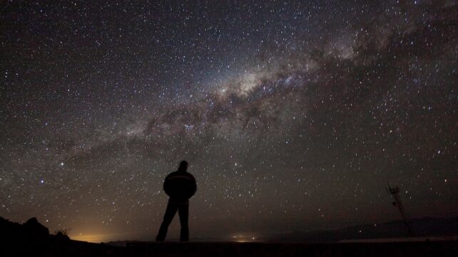silhouette of a person looking up at the night sky