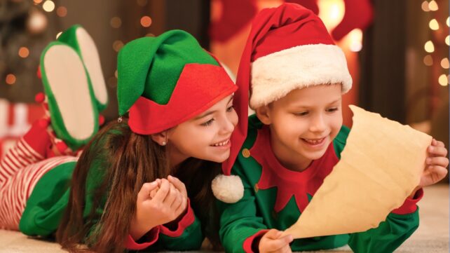 Children in christmas outfits reading a scroll