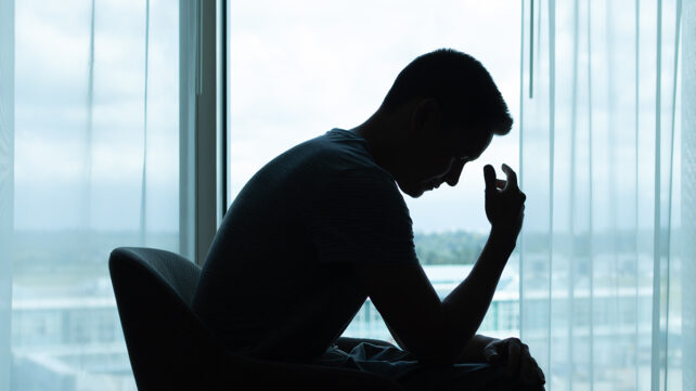 Thoughtful man in a dark room with head down