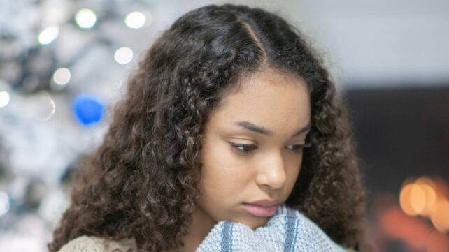 A young person looking unwell or sad in a Christmassy room