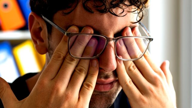 man rubs eyes
