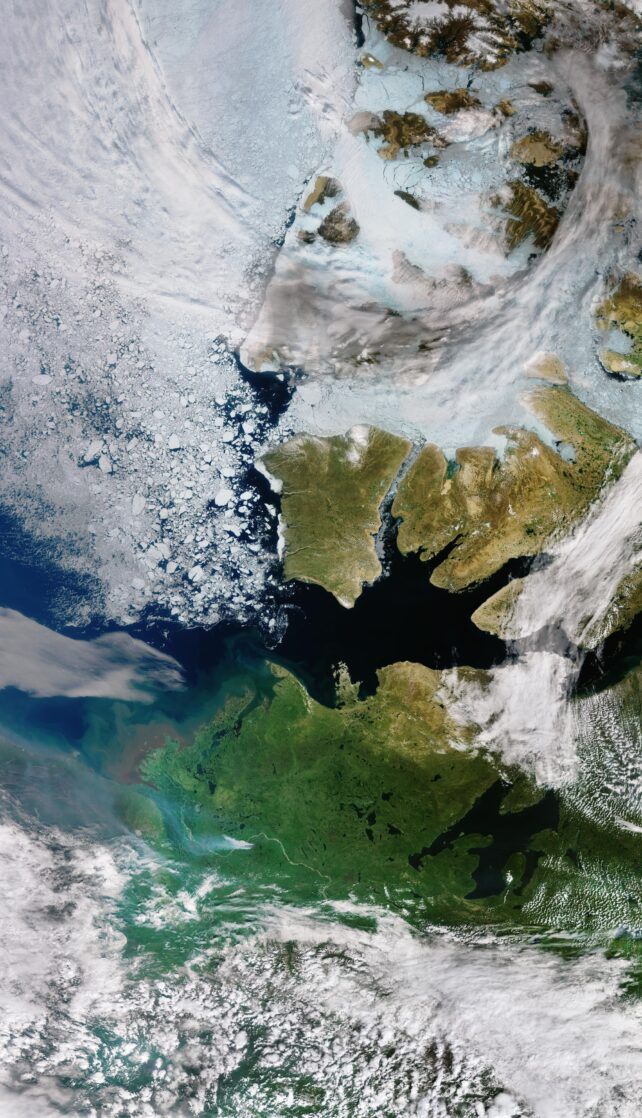 Satellite image of Arctic islands, showing clouds, sea ice, and wildfire smoke.