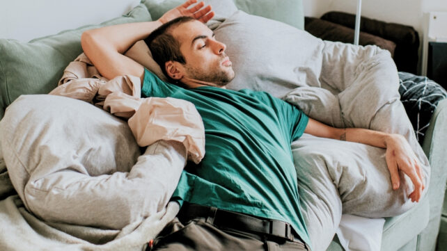A young man on the couch in an awkward-looking sitting position