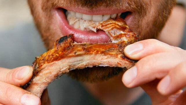 Close up of a man eating a barbeque rib