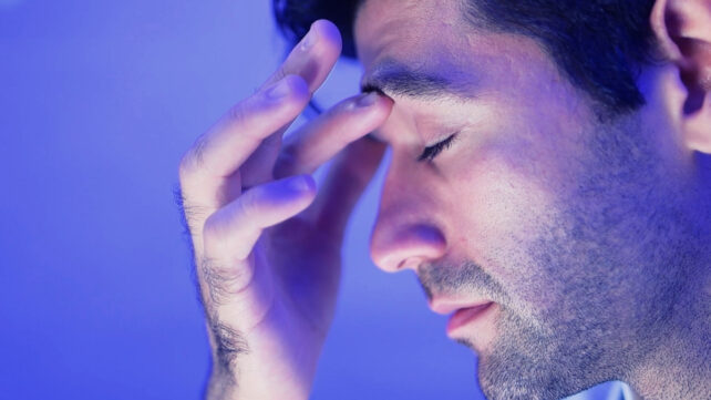 Tired man holding forehead with hand, side profile