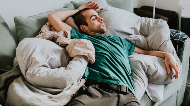 Man sitting on couch in an awkward position 