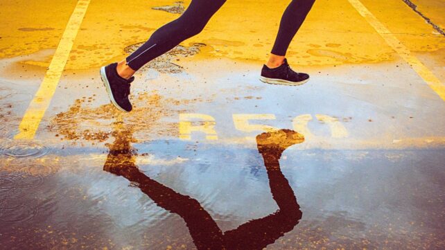 High angle view of a runner's legs and their reflection in the water of a parking lot