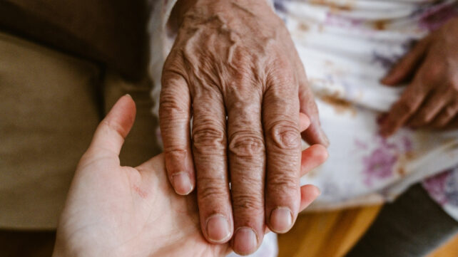 elderly person's hand being held by a younger person