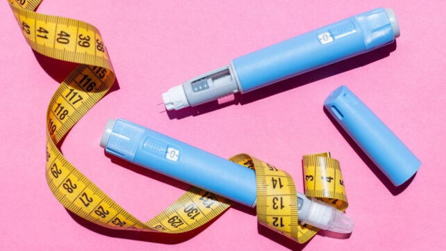 semaglutide pen and measuring tape on a pink background