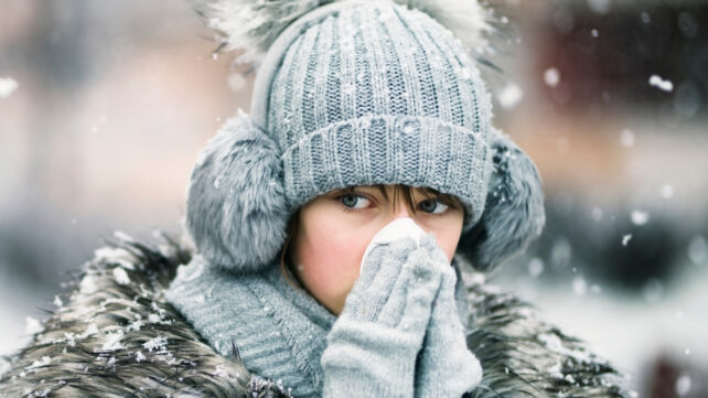 woman outside in winter blowing her nose