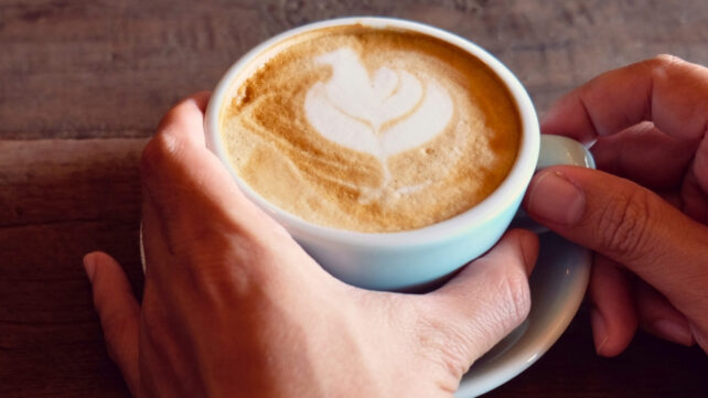 Hands holding a rustic looking coffee cup 