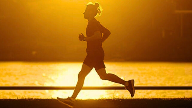 silhouette of a person running by a river