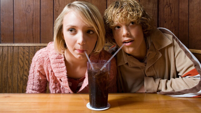 two teens drinking a soda