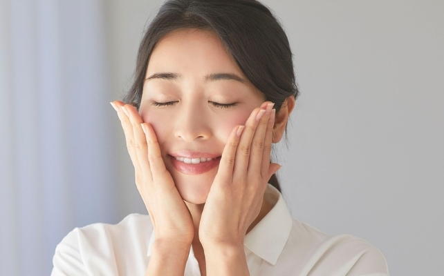 woman touching her own face with her eyes closed