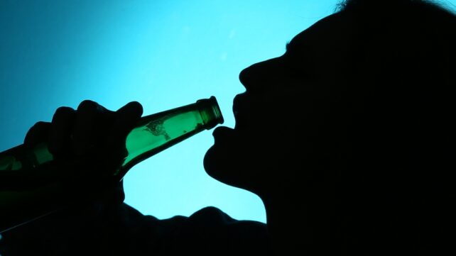 Silhouette of a person drinking from a bottle