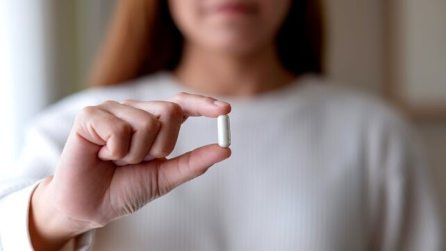 woman holds pill