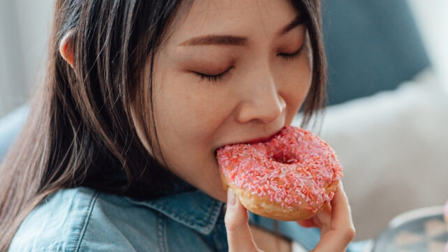 woman eating a pink donut