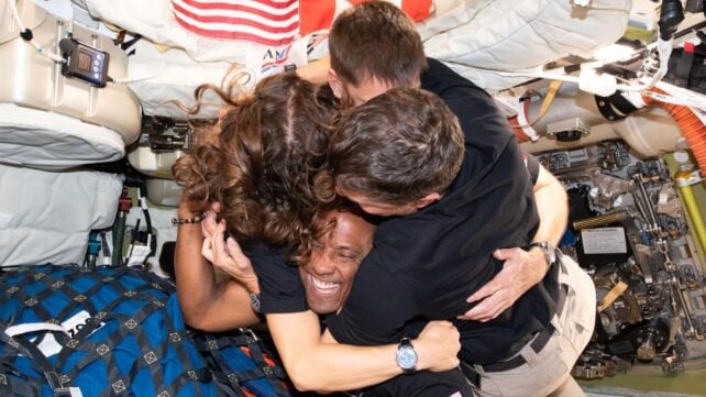 The Artemis II crew having a group hug inside the Orion spacecraft