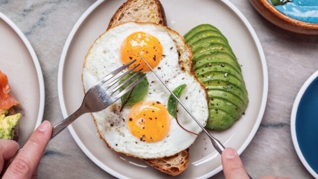 Person eating healthy colourful breakfast at a cafe, high angle view of two eggs on toast