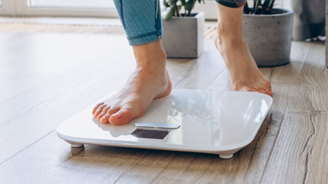 Close-up of bare feet stepping onto a digital scale