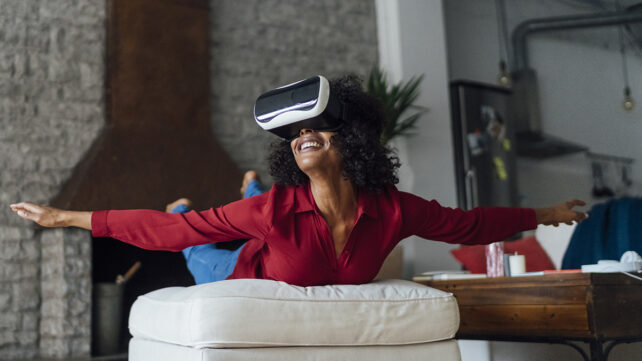 Woman lying on seating furniture, wearing VR goggles