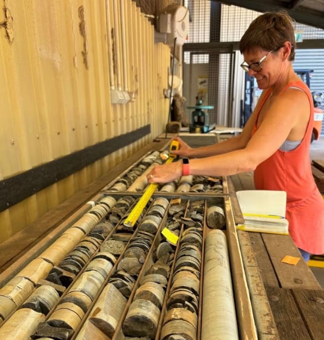 A researcher measures cylindrical rock cores stored in trays at the Northern Territory Geological Survey warehouse in Darwin, Australia.