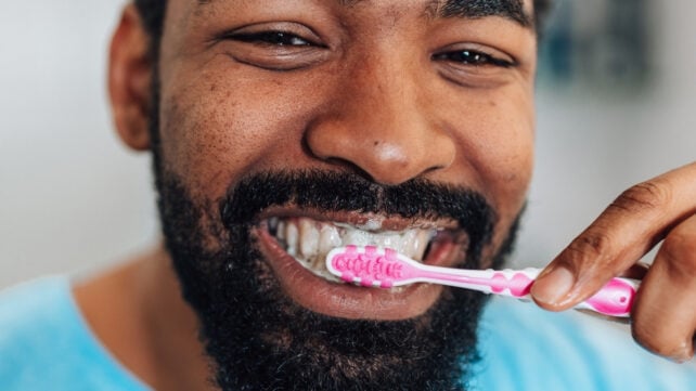 Close up of smiling african american man brushing teeth