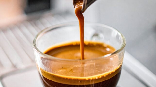 Espresso being poured into a clear cup, close view