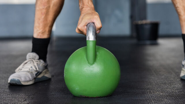 A muscular male athlete prepares for a kettlebell lift