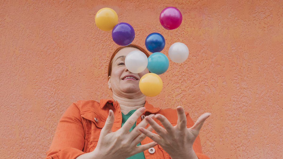 Mature woman juggling multicolored balls