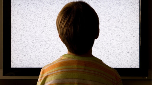 Back view of a child looking at a TV with static on the screen