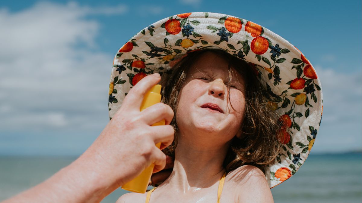 A parent applies sunscreen to a child's face