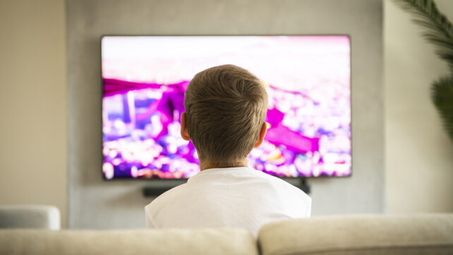 A boy sitting on a sofa and watching TV