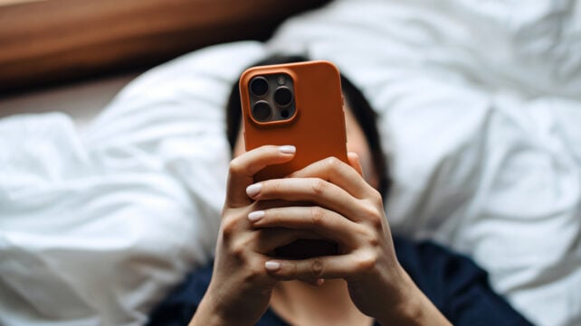 Someone using a smartphone in bed