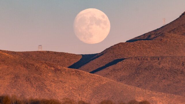 Full moon rising over mountains at dusk
