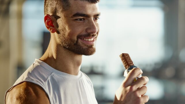 male athlete holding chocolate bar during sports training in a gym