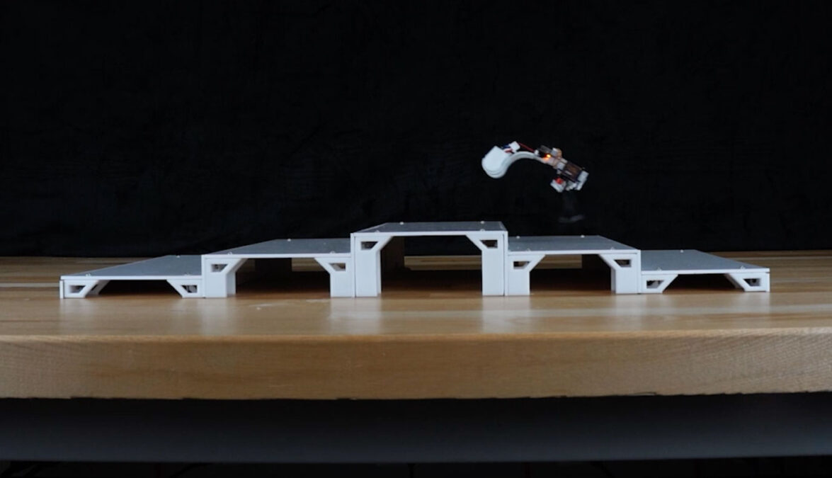 A small robot captured in mid-air while hopping across miniature white steps