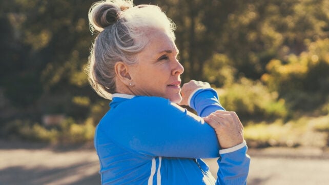 Mature woman stretching before exercise on sunny day