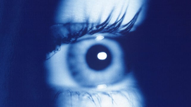 Close up of a human eye shadowed in contrasting dark blue light